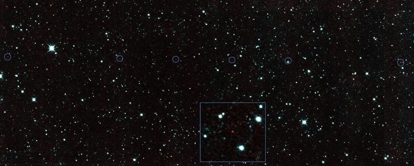 A rugged asteroid drifts against a dense field of bright stars in deep space.